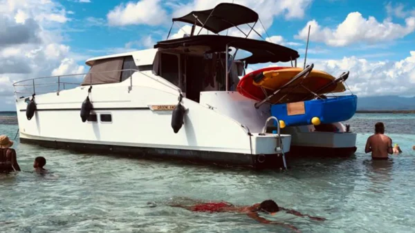 Catamaran à moteurs ancré dans les eaux peu profondes du Grand-Cul-de-Sac-Marin, avec paddles et kayaks à bord.