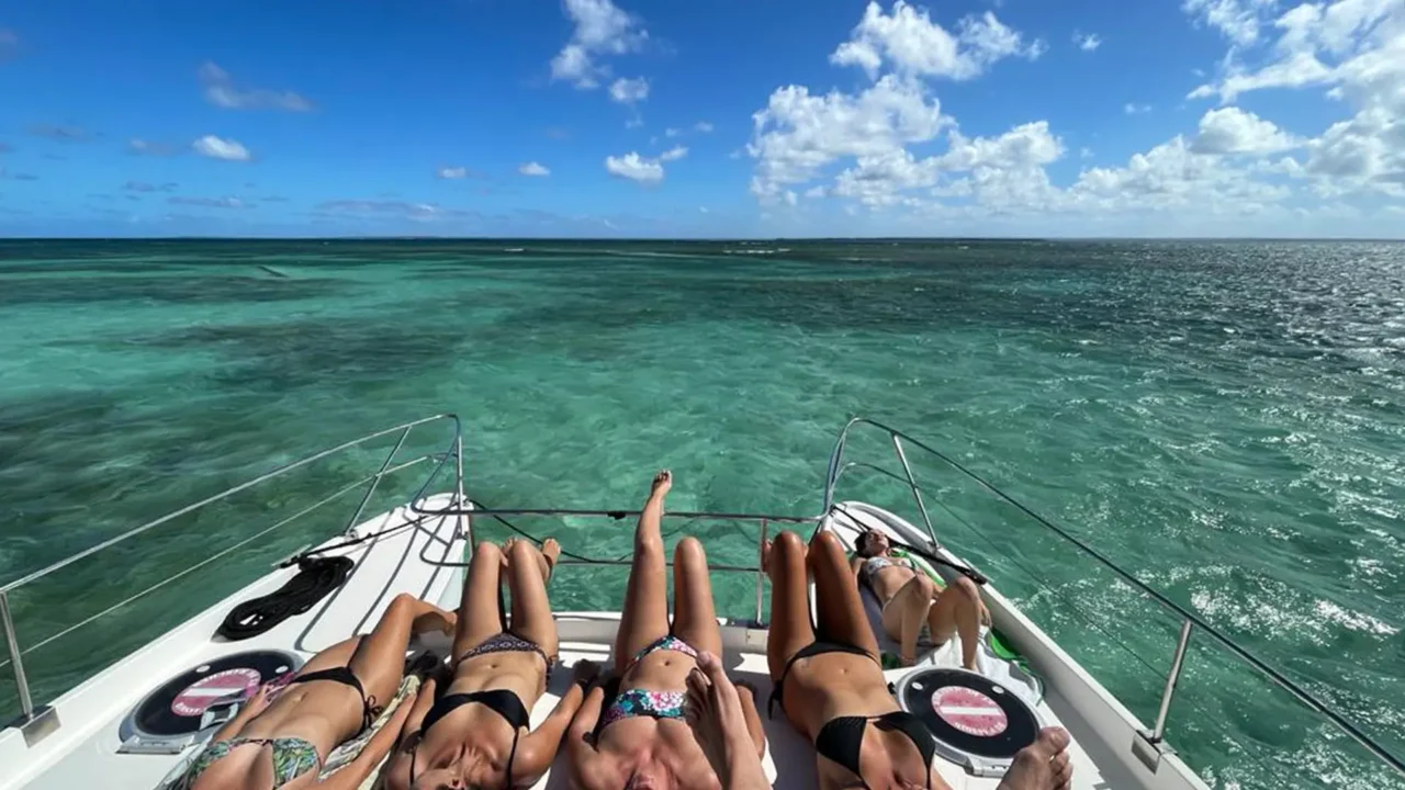 Passagers profitant du soleil à l’avant d’un catamaran à moteurs dans les eaux turquoise du Grand-Cul-de-Sac-Marin en Guadeloupe.